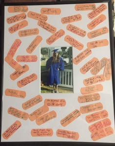 a man in blue cap and gown standing next to a white board with orange writing on it