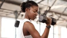 a woman lifting two dumbs in a gym