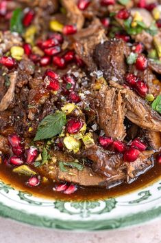 a plate with meat and pomegranates in sauce on top of it