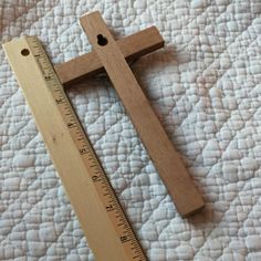 a wooden cross sitting on top of a bed next to a tape measure ruler in front of it