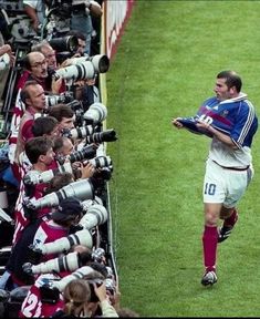 a soccer player is surrounded by photographers and cameramen as he walks across the field