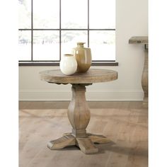 a wooden table with two vases on it in front of a window and wood flooring