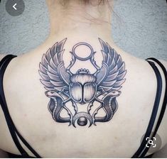 the back of a woman's neck with an insect tattoo on it and wings