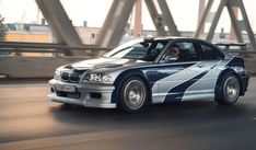 a white and blue car driving down a street next to a bridge with tall buildings in the background