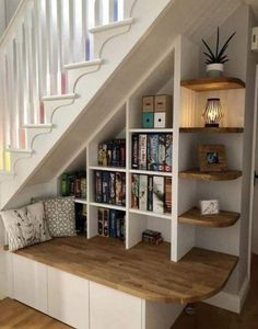 an under the stairs bookshelf with lots of books on it and shelves below