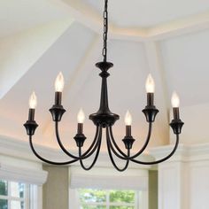 a chandelier hanging from the ceiling in a room with white walls and windows