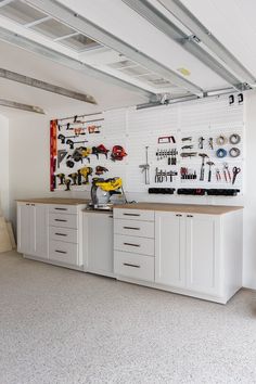 a garage with white cabinets and tools hanging on the wall above it is also a workbench