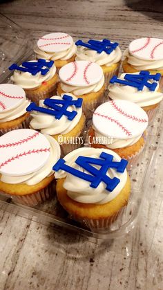 cupcakes with frosting and baseball designs on them sitting in a plastic container