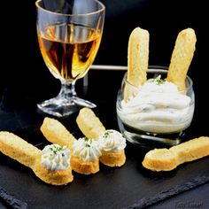 some food is laying out on a black cloth next to a wine glass and two glasses