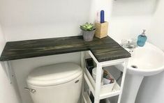 a white toilet sitting next to a sink under a wooden counter top in a bathroom