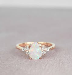 a white opal and diamond ring sitting on top of a table