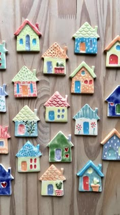 many small houses are painted in different colors and shapes on a wooden surface with wood planks behind them