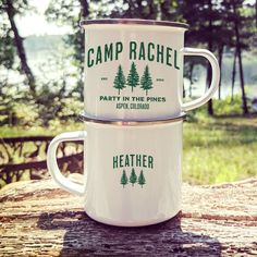 two white camp mugs sitting on top of a wooden table