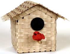 a birdhouse made out of woven material with a black hole in the roof and a red cardinal on it's nose