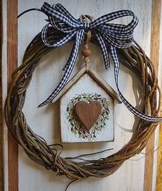 a wreath with a birdhouse hanging on the side of a door that has a wooden heart in it