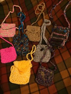 many crocheted purses are laying on a plaid tablecloth and one has a cross - body bag in the middle