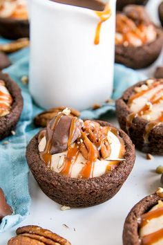 chocolate cookies with caramel drizzle and pecans are on a blue cloth