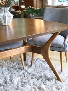 a wooden table with two chairs and a vase on top of it in a living room