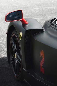 the front end of a black sports car with red stripes and number 2 on it