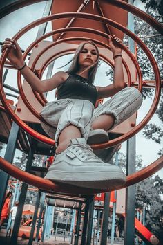 a woman sitting on top of a metal ring in a playground with her feet up