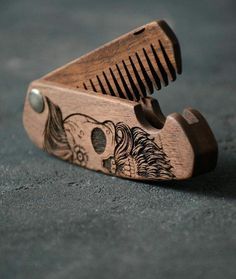 a wooden comb with designs on it sitting on the ground next to a pair of scissors