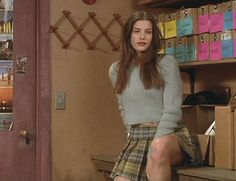 a woman sitting on top of a wooden bench next to a book shelf filled with books