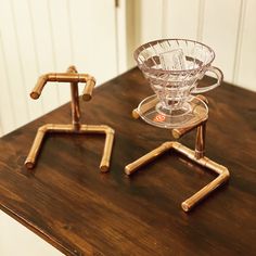 two glass vases sitting on top of a wooden table next to eachother