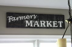 a sign that says farmers market hanging on the wall next to a lamp and window