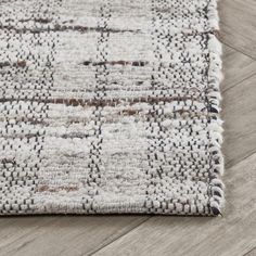 an area rug with grey and white colors on the wooden floor, close up view