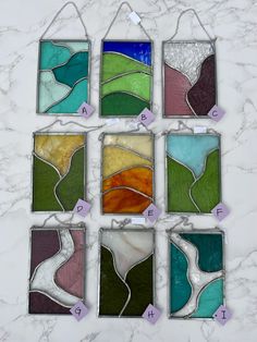 six different stained glass pieces hanging on a marble counter top with instructions for how to make them