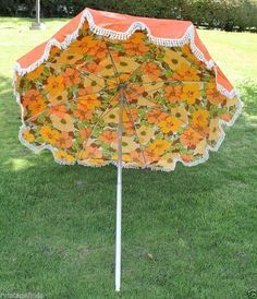 an orange and white umbrella sitting in the grass