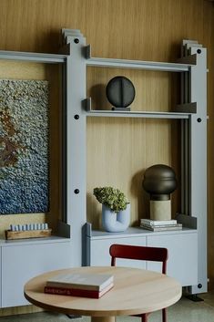 a table and chairs in front of a wall shelf with books on top of it