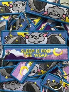 a pile of blue and purple key chains with cartoon cats on them that say sleep is for the weak