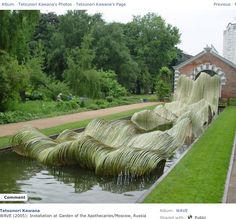 an art installation is displayed in the middle of a pond with grass growing on it