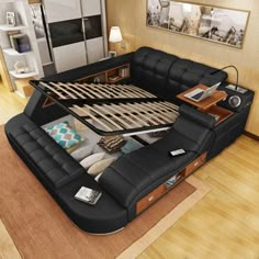 a large black leather bed sitting on top of a wooden floor next to a table