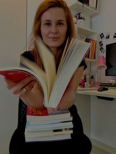 a woman holding a stack of books in her hands