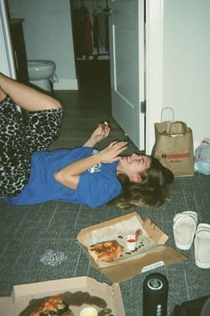 a woman laying on the floor in front of pizza boxes