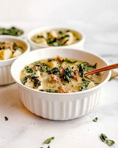 three white bowls filled with food on top of a marble counter topped with spinach