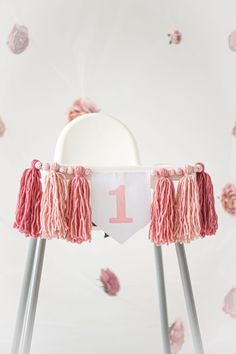 a white chair with pink tassels and a number one banner on it's back