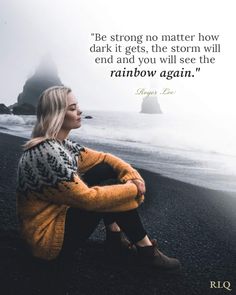 a woman sitting on top of a black beach next to the ocean with a quote