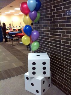 some dices and balloons in front of a brick wall