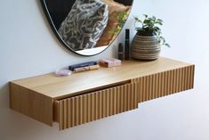 a mirror on the wall above a wooden shelf