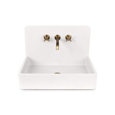 a white sink with two brass faucets on the front and bottom, against a white background