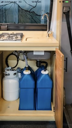 two blue and white containers under a sink on a shelf next to a wall mounted mirror