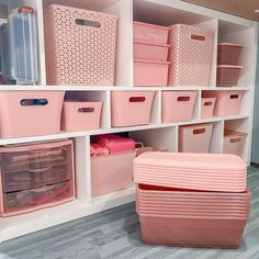 the shelves are filled with pink bins and baskets