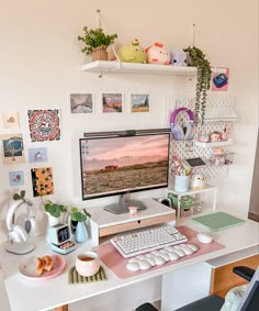 a desk with a computer, keyboard and various pictures on the wall in front of it