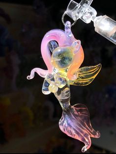 a glass figurine hanging from a hook with an empty bottle in the background