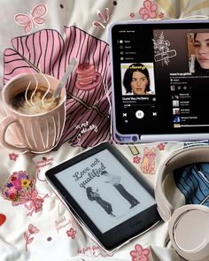 an open laptop computer sitting on top of a bed next to a cup of coffee