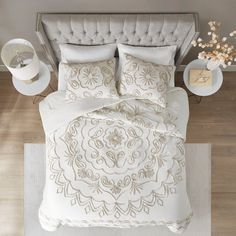 the bed is made with white linens and has an intricate design on it,