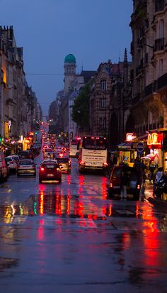 a city street filled with lots of traffic on a rainy day in the middle of town